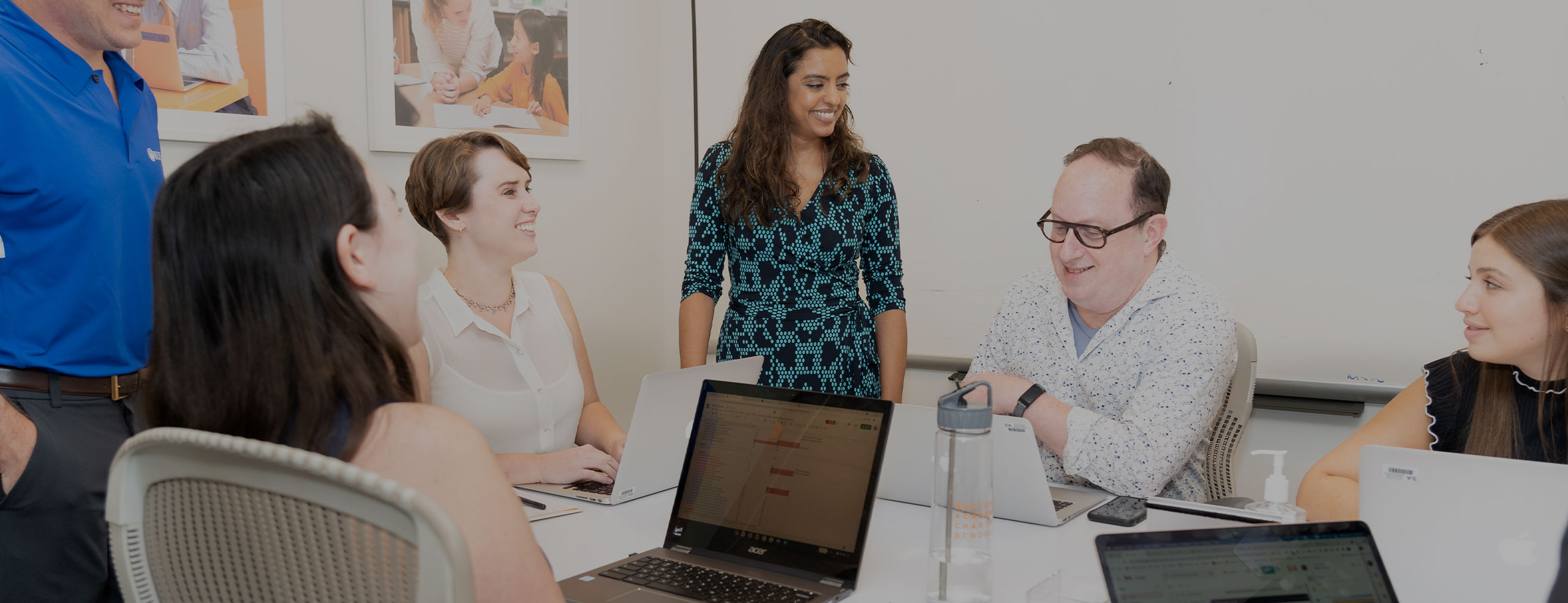 A diverse group of six professionals, including men and women, are gathered around a conference table in the SA network office, engaged in a discussion.